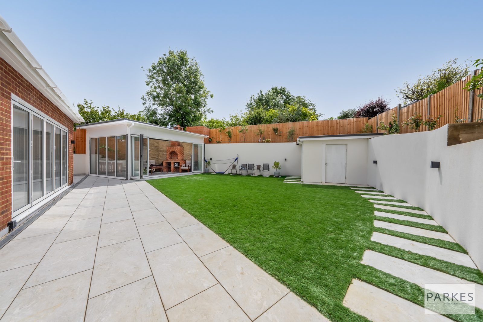 Landscaped rear garden with lawn, stone paving and planted borders