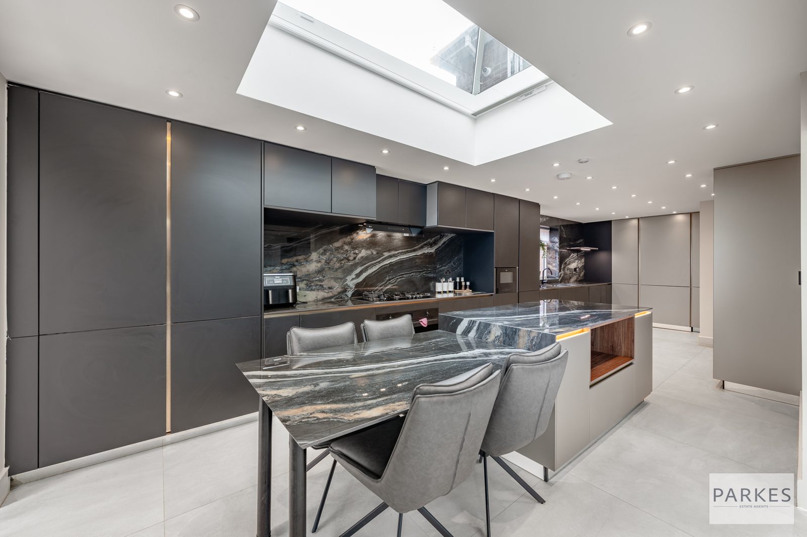 Handleless kitchen with an island and a full-height marble splashback